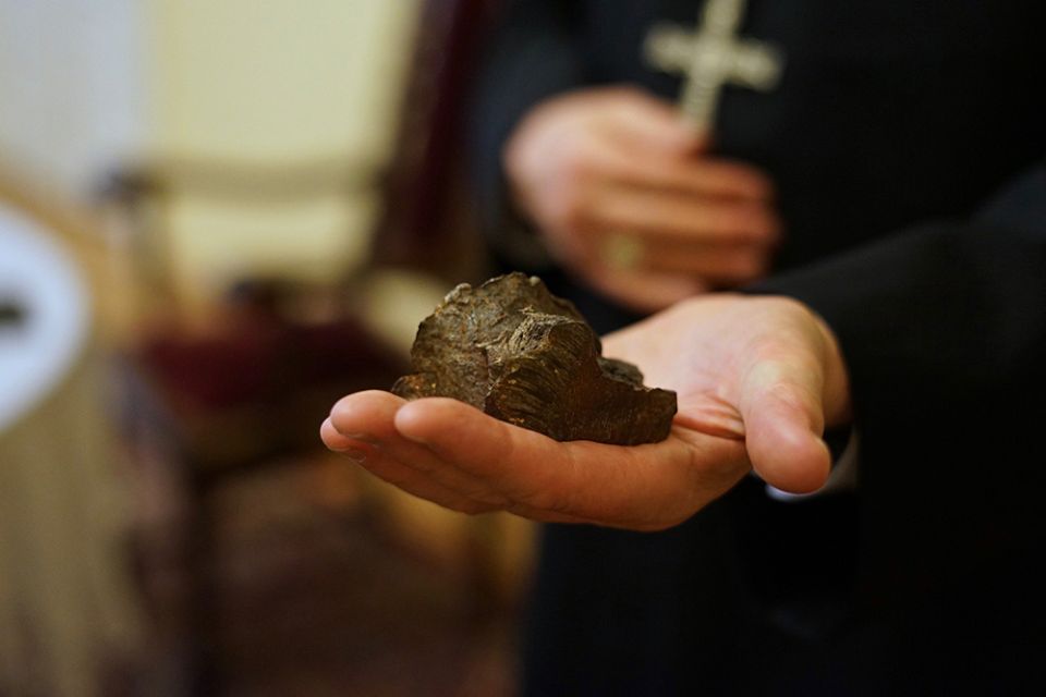 Archbishop Stanislaw Budzik of Lublin, Poland, is seen in his office April 22, holding what he said is a piece of the bomb that struck the roof of the chancery of the Diocese of Kharkiv-Zaporizhia, Ukraine, March 1. (CNS/Adrian Kowalewski)