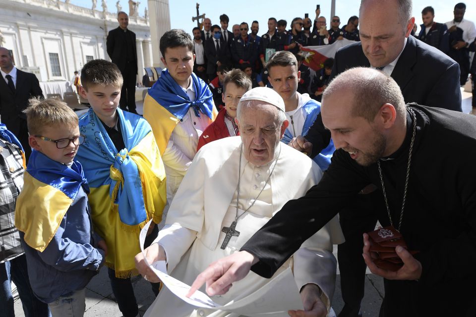 Father Volodymyr Medvid, a chaplain and head of Caritas of the Ukrainian Greek Catholic Church, shows Pope Francis artwork while meeting with a group of Ukrainians after his weekly general audience in St. Peter's Square at the Vatican April 27, 2022. (CNS