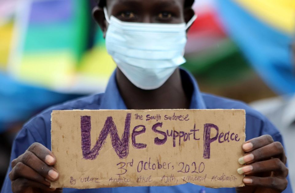 A civilian holds a placard as he celebrates the signing of peace agreement between Sudan's transitional government and Sudanese revolutionary movements to end decades-old conflict, in Juba, South Sudan, in this Oct. 3, 2020, file photo. 