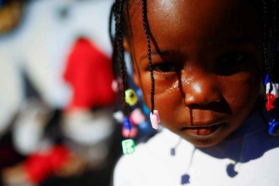 A young Haitian migrant girl traveling with her parents, seeking to reach the U.S., stands outside a temporary shelter at a church in Ciudad Juárez, Mexico, Dec. 20, 2021. (CNS/Reuters/Jose Luis Gonzalez)