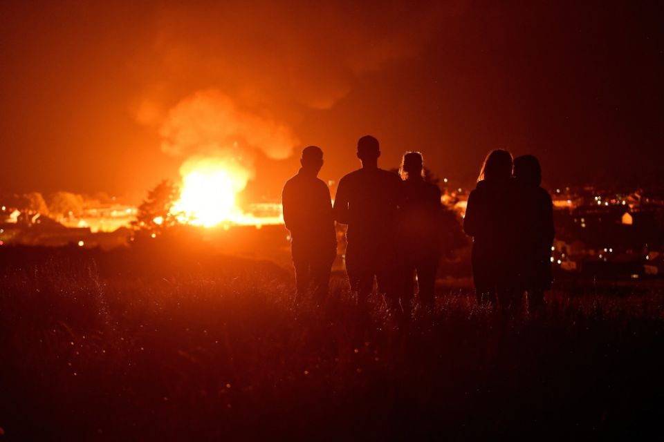 People watch as the completed Craigyhill bonfire burns on the '11th night' to usher in the 12th of July celebrations in Larne, Northern Ireland, July 11. (CNS/Reuters/Clodagh Kilcoyne)