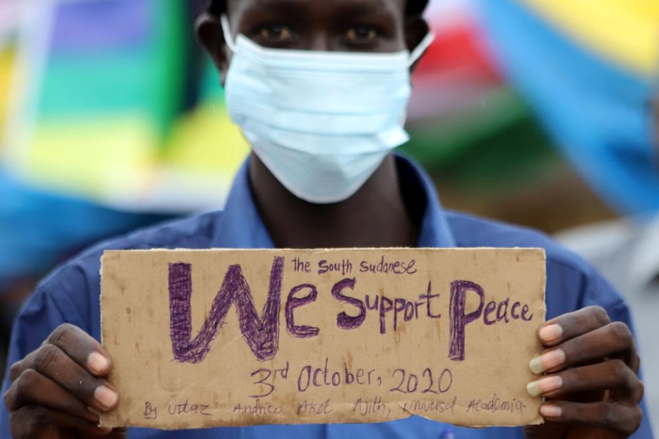 A civilian holds a placard in support of peace as he celebrates the signing of peace agreement between Sudan's transitional government and Sudanese revolutionary movements to end decades-old conflict, in Juba, South Sudan, in this Oct. 3, 2020, file photo