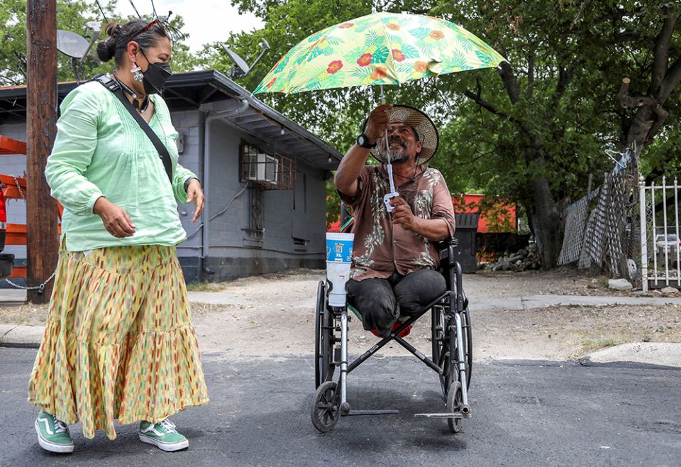 Susana Segura, with Bread and Blankets Mutual Aid, left, gives out water, bananas and hats to unhoused people and others in need during a heat advisory July 21 in San Antonio. (CNS/Reuters/Lisa Krantz)