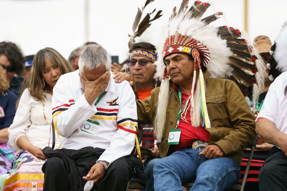 A man is comforted by an Indigenous leader during ceremonies in Maskwacis, Alberta, July 25, 2022, where Pope Francis apologized to Canada's native people on their land for the church's role in schools where Indigenous children were abused. (CNS photo/Ada