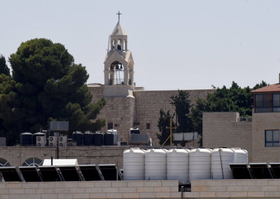 Black and white tanks, each capable of holding 1,500 liters of water, rest on top of a school near the Church of the Nativity in Bethlehem, West Bank, Aug. 22, 2022. Israel has strict control of water sources for Palestinians. (CNS photo/Debbie Hill)