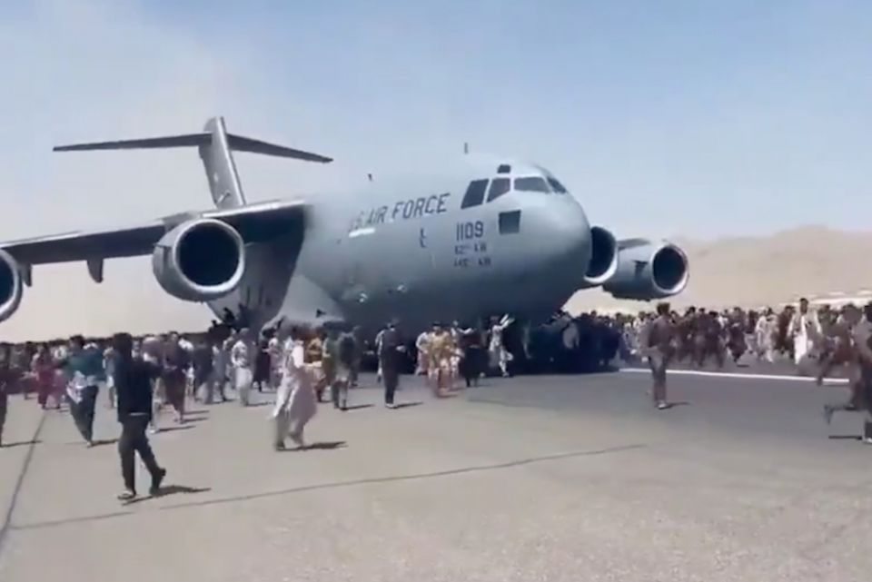 Hundreds of people run alongside a U.S. Air Force C-17 transport plane as it moves down a runway of the international airport Aug. 16 in Kabul, Afghanistan. (AP/video screengrab via Twitter/@Mukhtarwafayee) 