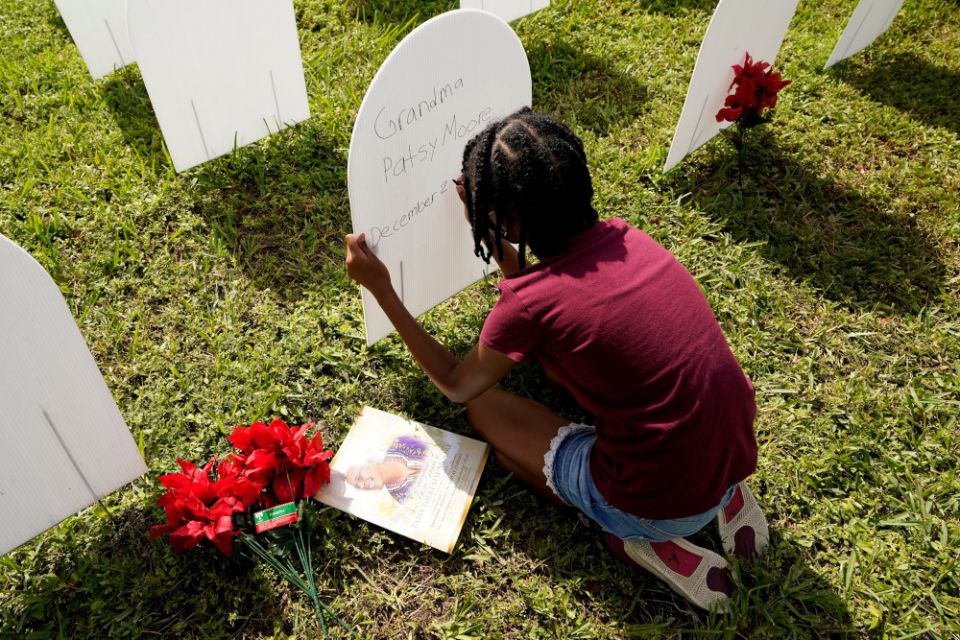 Kyla Harris, 10, writes a tribute Nov. 24 to her grandmother Patsy Gilreath Moore, who died at age 79 of COVID-19, at a symbolic cemetery created to remember and honor lives lost to COVID-19 in the Liberty City neighborhood of Miami. (AP/Lynne Sladky)