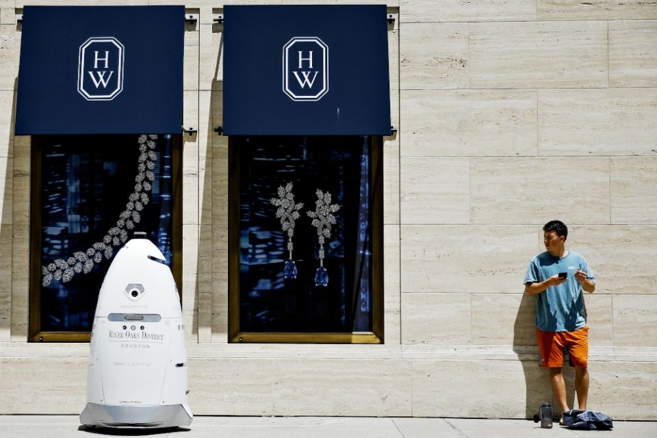 A new security robot drives toward Daniel Webb as it patrols the sidewalks and parking garage of the River Oaks District shopping complex Aug. 18 in Houston. (AP/Houston Chronicle/Michael Ciaglo)