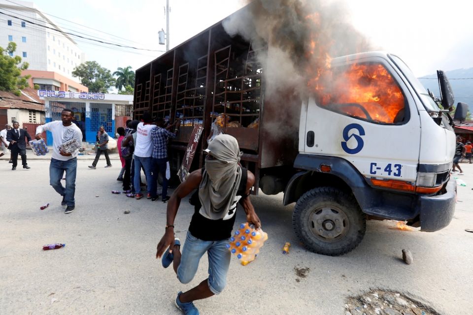 Demonstrators loot a burning truck after deadly protests to demand the resignation of Haitian President Jovenel Moise in Port-Au-Prince Nov. 19, 2019. (CNS/Reuters/Jeanty Junior Augustin)