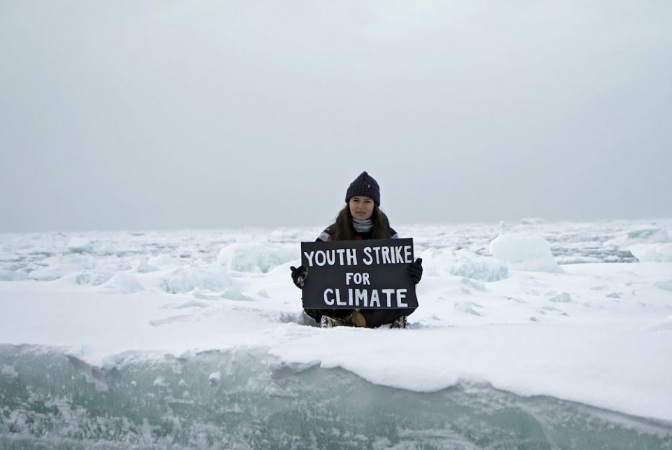 Environmental activist and campaigner Mya-Rose Craig, 18, holds a cardboard sign reading "youth strike for climate" as she sits on the ice floe in the middle of the Arctic Ocean, hundreds of miles above the Arctic Circle, Sept. 20. (CNS/ Reuters/Natalie T