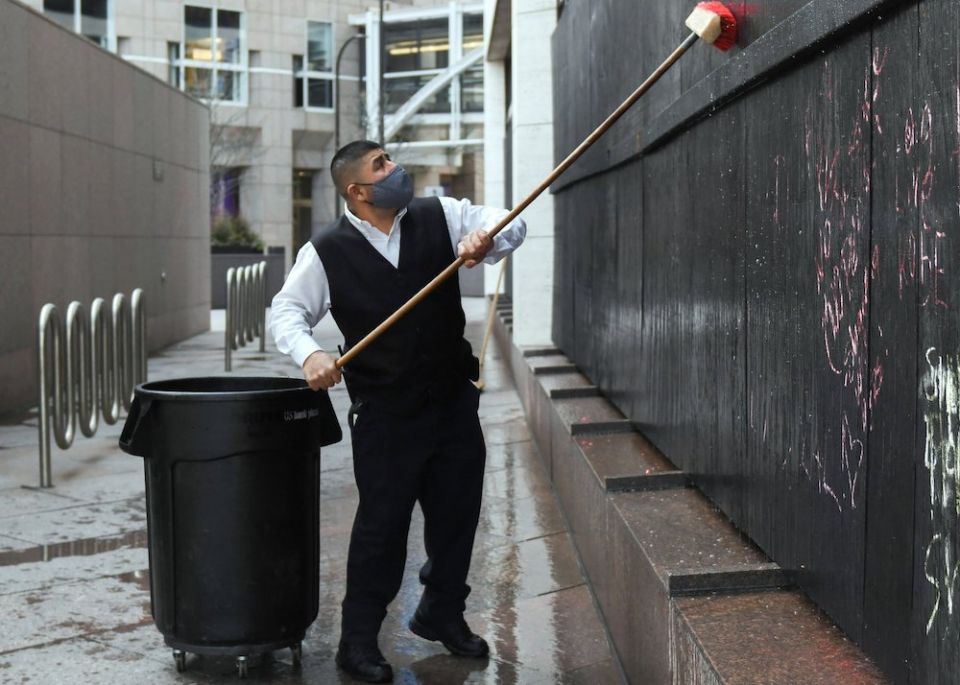 A worker in Minneapolis washes away chalked messages on US Bank Plaza March 8, 2021. (CNS/Reuters/Nicholas Pfosi)