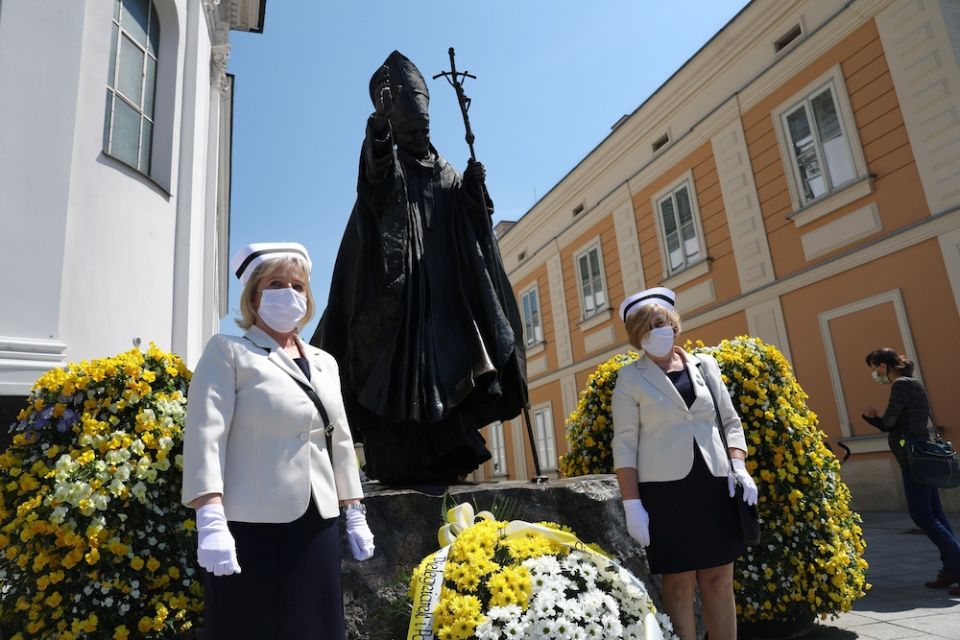 Nurses in protective masks stand in front of a statue of St. John Paul II in Wadowice, Poland, May 18, during a ceremony to commemorate the 100th anniversary of the late pope's birth. (CNS/Agencja Gazeta via Reuters/Dawid Zuchowicz)