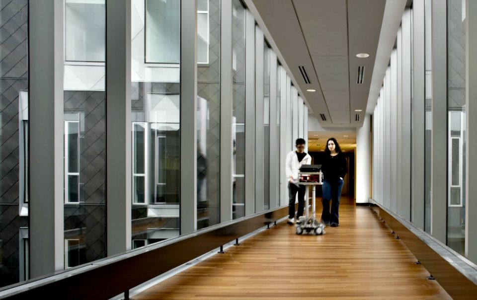 A mobile CoBot, or collaborative robot, leads students across a walkway bridge on the campus of Carnegie Mellon University in Pittsburgh. (Carnegie Mellon University)