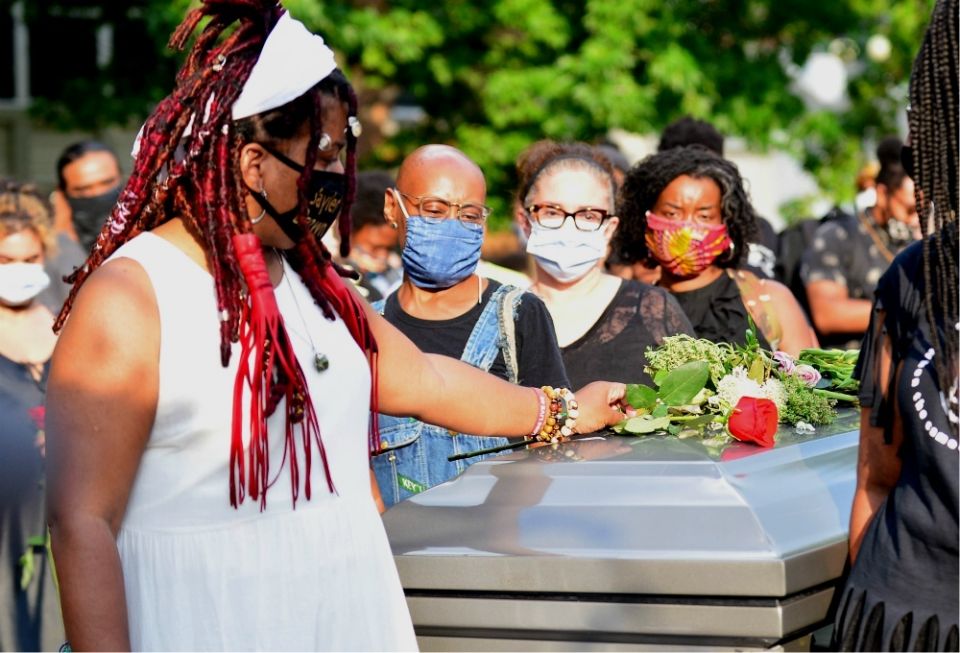 Dannielle Brown places flowers on an empty casket during her "living funeral" in Pittsburgh on Aug. 6, more than a month into her hunger strike. Brown told NCR on Aug. 31 that she is not sure she will survive her strike, and that she wants to be remembere