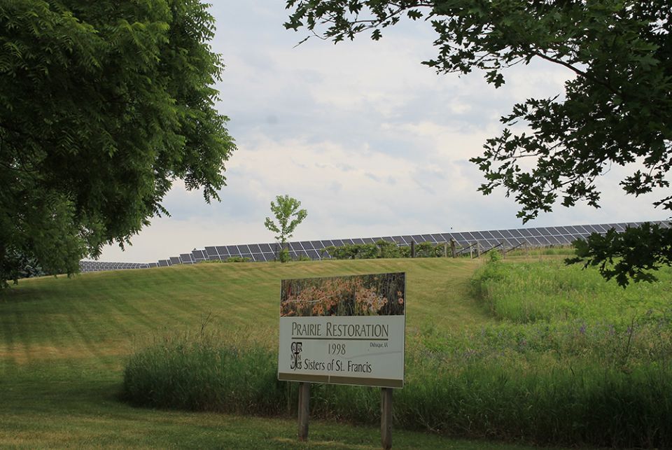 An array of 2,600 solar panels in the background of a restored prairie area at the motherhouse of the Sisters of St. Francis, in Dubuque, Iowa. (EarthBeat photo/Brian Roewe)