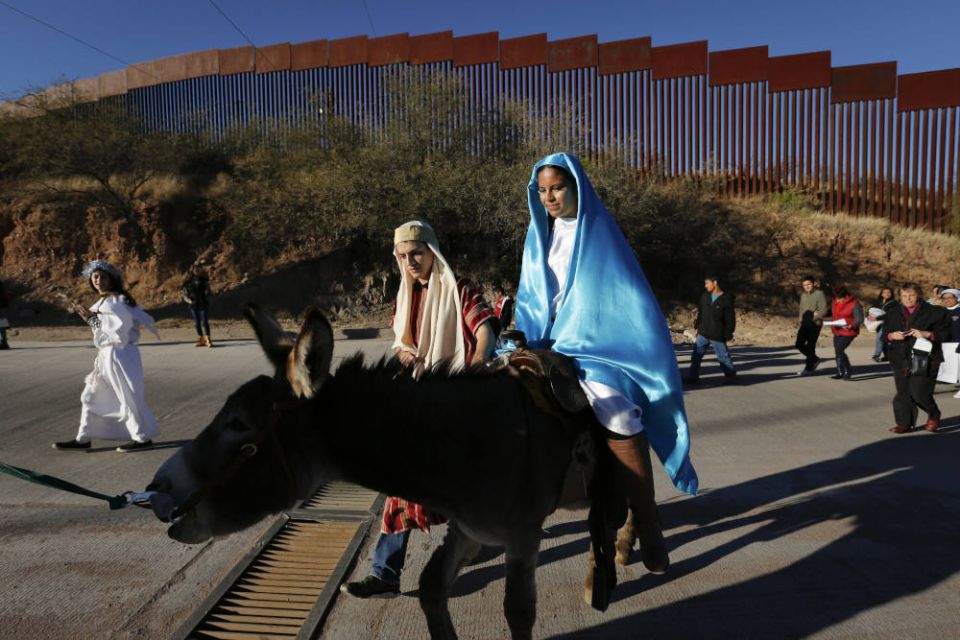 Saul Gonzalez and Kenia Salas play the parts of Joseph and Mary as they make their way along the international border fence in Nogales, Mexico, Dec. 20, 2015, as they participate in a traditional Mexican Las Posadas. (CNS photo/Nancy Wiechec)