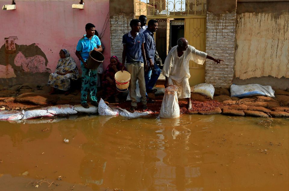 Men stand in floodwaters following heavy rains in Khartoum, Sudan. East Africa is struggling under a cascade of impacts from torrential rains, locusts and the coronavirus pandemic. (CNS photo/Mohamed Nureldin Abdallah, Reuters)