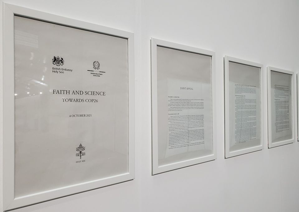 Framed pages of a letter from Pope Francis and nearly 40 other faith leaders, delivered to COP26 leaders on Oct. 4, hang on a wall between the two plenary halls where meetings are taking place. (EarthBeat photo/Brian Roewe)