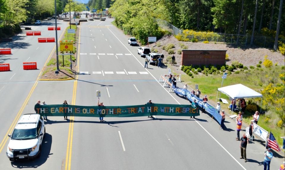 Protesters hold a banner while blocking the Main Gate entrance to Naval Base Kitsap-Bangor May 12 as part of a protest against the Trident submarine base in honor of Mother's Day for Peace. (Ground Zero Center for Nonviolent Action/Glen Milner)