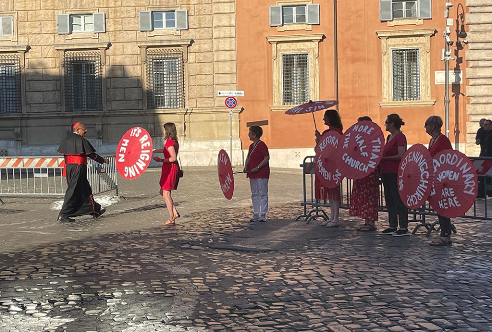 Women's ordination advocates witness outside the entrance to the Vatican's Paul VI Hall on Aug. 29. At left, Kate McElwee approaches a cardinal entering the consistory meeting with Pope Francis. (NCR photo/Christopher White)