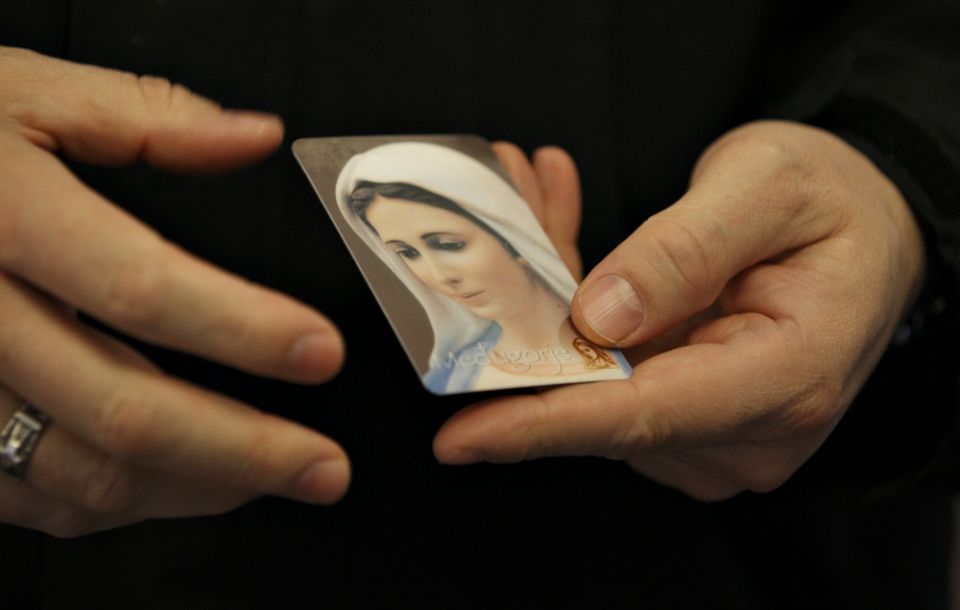 A priest holds an image of Mary in Medjugorje, Bosnia-Herzegovina, in 2011. (CNS/Paul Haring)