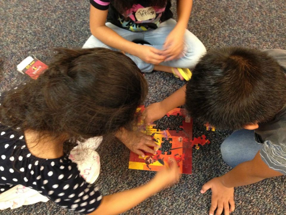 Three young guests of Annunciation House's Casa del Refugiado in El Paso, Texas, work on a jigsaw puzzle in the Cuarto de Niños, a large play space for children. (Petrina Grube)