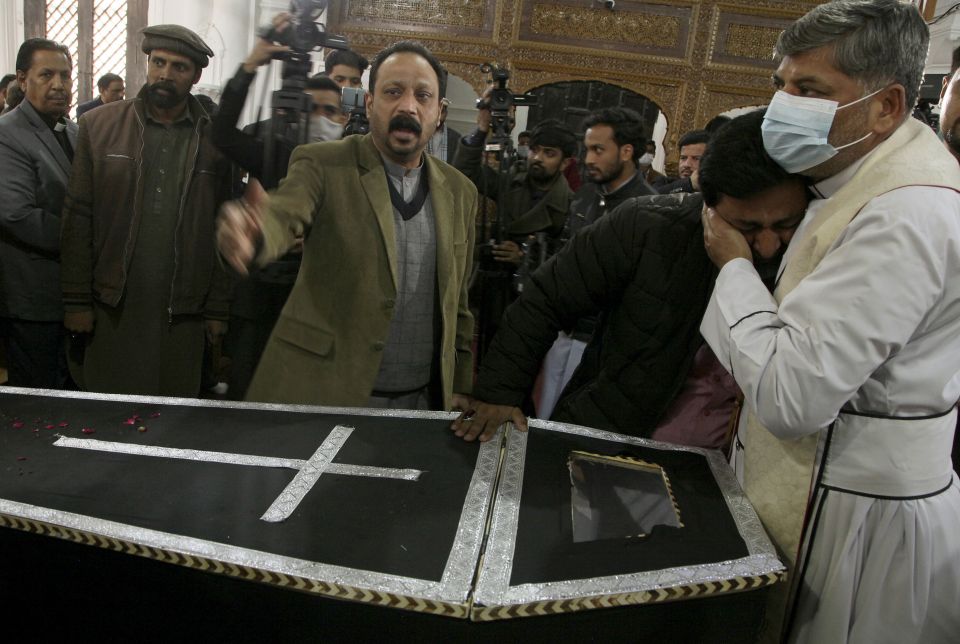 A clergyman comforts a relative of Christian priest Father William Siraj, 75, who was killed by gunmen, during his funeral service at the All-Saints Church, in Peshawar, Pakistan, Jan. 31, 2022. (AP Photo/Muhammad Sajjad)