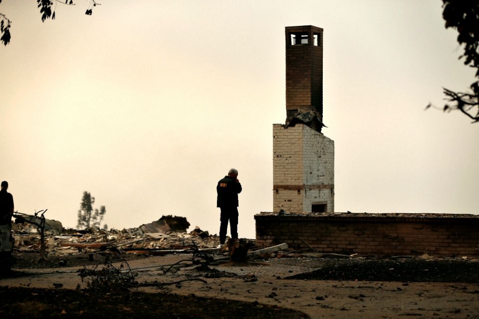 A Butte County Sheriff deputy surveys a home Nov. 11 that was destroyed by the Camp Fire in Paradise, Calif. (CNS/Reuters/Stephen Lam)