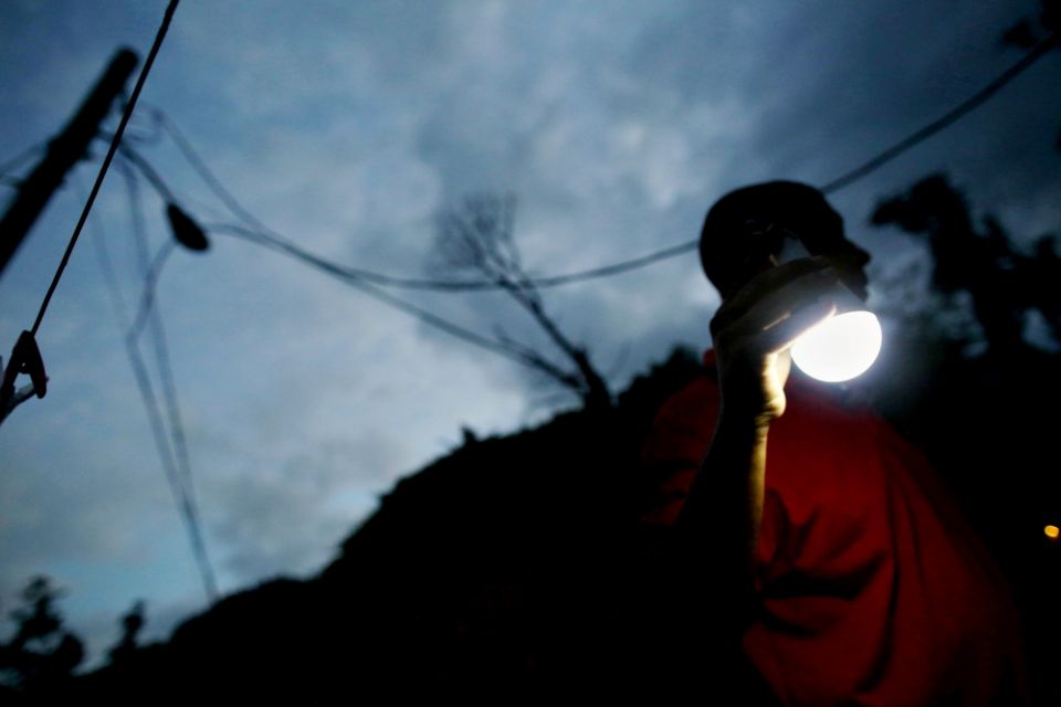 A man uses a solar lamp while walking in the dark May 11 in Jayuya, Puerto Rico, where the fragile power system was still reeling from the devastation caused by Hurricane Maria eight months before. (CNS/Reuters/Alvin Baez)