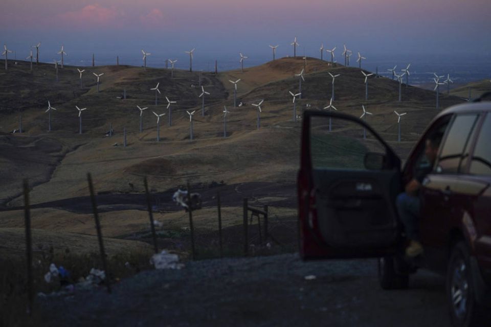A man looks out at wind turbines in Livermore, Calif., Wednesday, Aug. 10, 2022. Congress passed a transformative climate change bill on Aug. 12. (RNS/AP Photo/Godofredo A. Vásquez)
