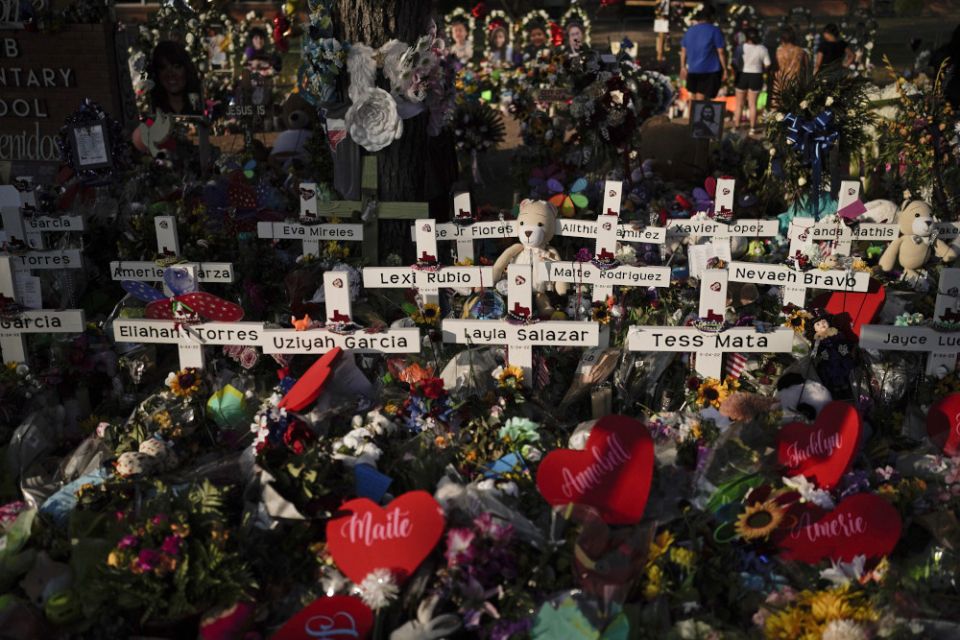 Flowers are piled around crosses with the names of the victims killed in a school shooting as people visit a memorial at Robb Elementary School to pay their respects May 31 in Uvalde, Texas. (AP/Jae C. Hong)