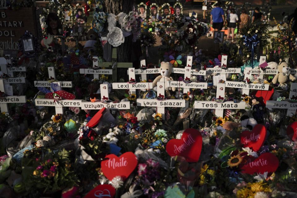 Flowers are piled around crosses with the names of the victims killed in a school shooting as people visit a memorial at Robb Elementary School to pay their respects May 31 in Uvalde, Texas. (AP/Jae C. Hong)