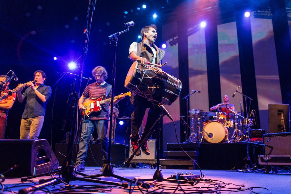 Holding the dhol (drum), Sunny Jain, founder of Red Baraat, jumps during a concert. (Courtesy of Red Baraat/Sachyn Mital)