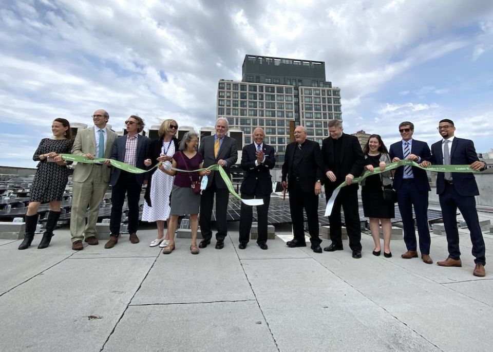 Flanked by staff of Catholic Charities Progress of Peoples Development Corp. and other partners, Bishop Nicholas DiMarzio of Brooklyn, New York, cuts the ribbon to inaugurate the new diocesan program to install solar arrays on public housing buildings. (C