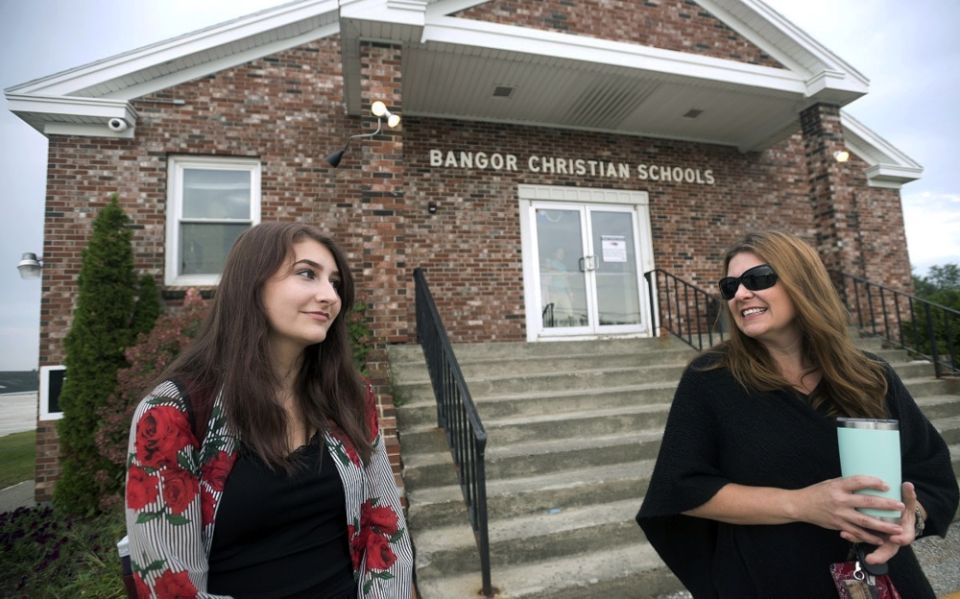 Former Bangor Christian Schools sophomore Olivia Carson, then 15, of Glenburn, Maine stands with her mother Amy while getting dropped off on the first day of school on August 28, 2018 in Bangor, Maine.