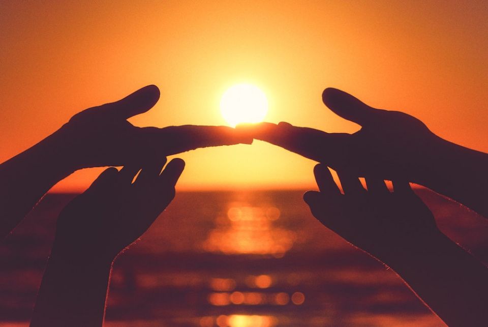 Hands touching, background of sunset (Unsplash/Alonso Reyes)