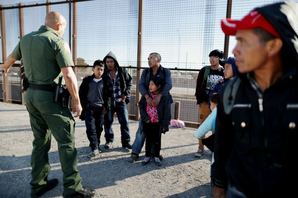 A group of Central American migrants is questioned about their children's health after surrendering to U.S. Border Patrol agents south of the U.S.-Mexico border fence in El Paso, Texas, March 6. (CNS/Reuters/Lucy Nicholson)
