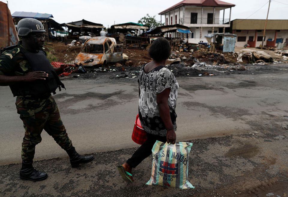 A woman walks past a soldier of the Cameroon army's elite Rapid Intervention Battalion in the city of Buea in the Anglophone Southwest Region Oct. 4, 2018. (Newscom/Reuters/Zohra Bensemra)