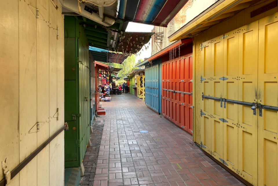 Shuttered shops on Olvera Street, Oct. 23. In the background, people sit outside a restaurant. (NCR photo/Lucy Grindon)