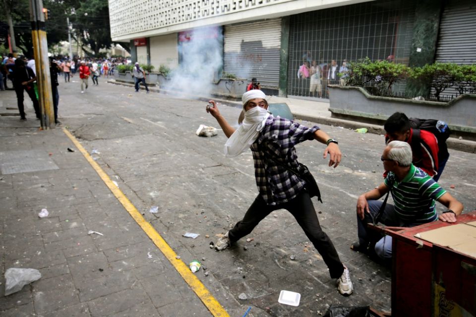 A demonstrator throws a tear gas canister back to riot police April 30 in Tegucigalpa, Honduras, during a protest against government plans to privatize health care and education. (CNS/Reuters/Jorge Cabrera)