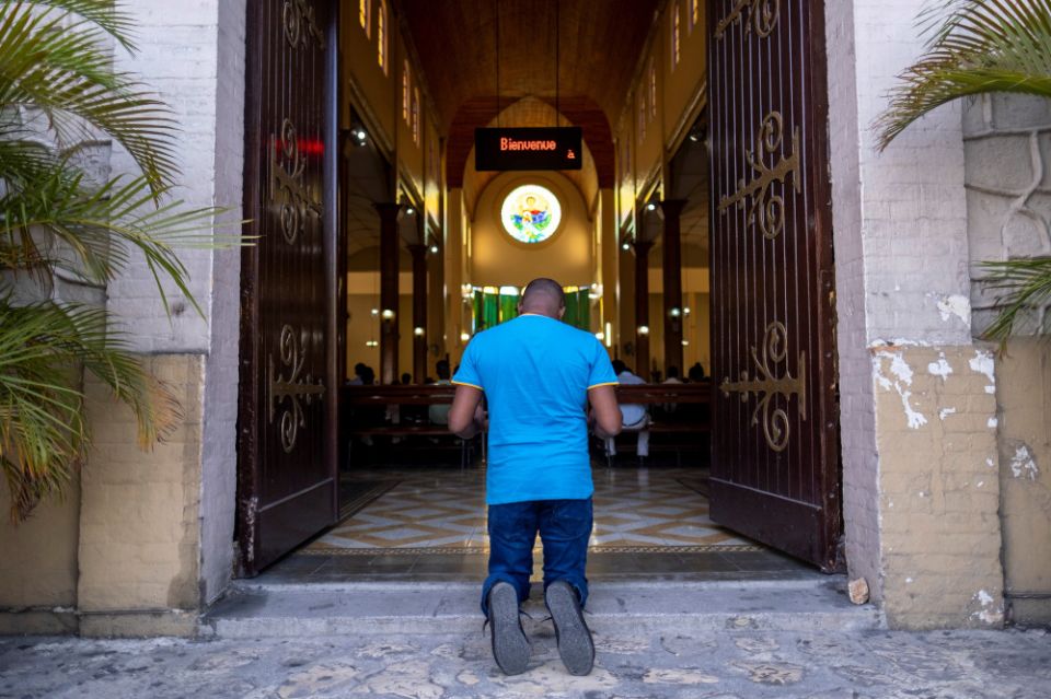 A man prays at the entrance of a church during Mass in Port-au-Prince, Haiti, July 11 following the assassination of Haitian President Jovenel Moïse July 7. (CNS/Reuters/Ricardo Arduengo)