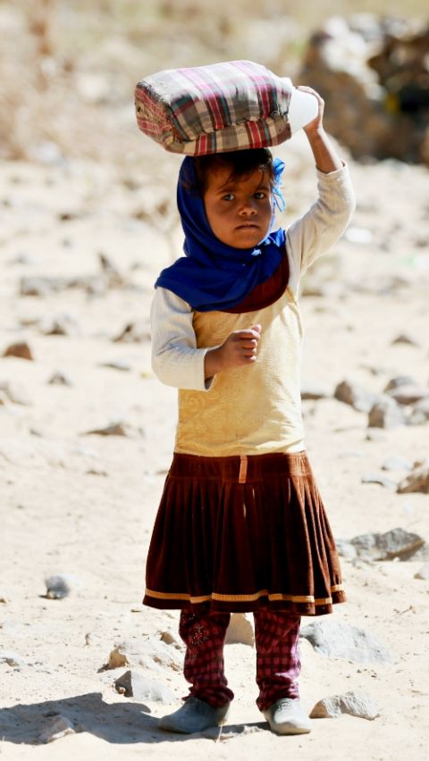 A displaced Yemeni girl carries a water container March 29 at a refugee camp located between Marib and Sanaa, Yemen. (CNS/Reuters/Ali Owidha)