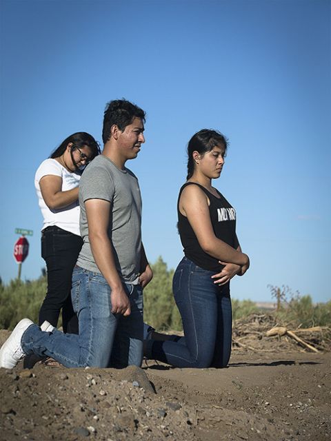 Migrant farmworkers kneel in prayer during an outdoor Mass Sept. 26, 2019, in Hatch, New Mexico, part of a pastoral encounter by U.S. bishops with migrants at the border. (CNS/Tyler Orsburn)