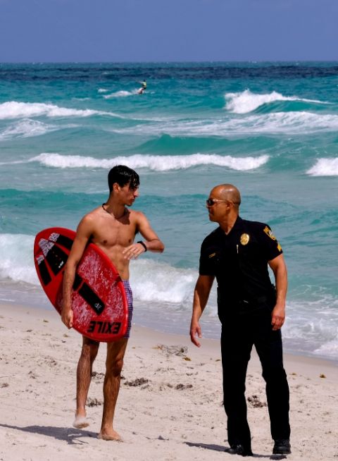 A police officer in Miami talks to a tourist about the closing of the beach due to coronavirus March 19. (CNS/Reuters/Maria Alejandra Cardona)