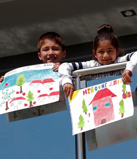 Children display their drawings from the balcony of their home in Thessaloniki, Greece, April 18, during the COVID-19 pandemic. The drawings in Greek read: "I want spring back" and "We stay home," Greece's national slogan during the pandemic. (CNS/Reuters