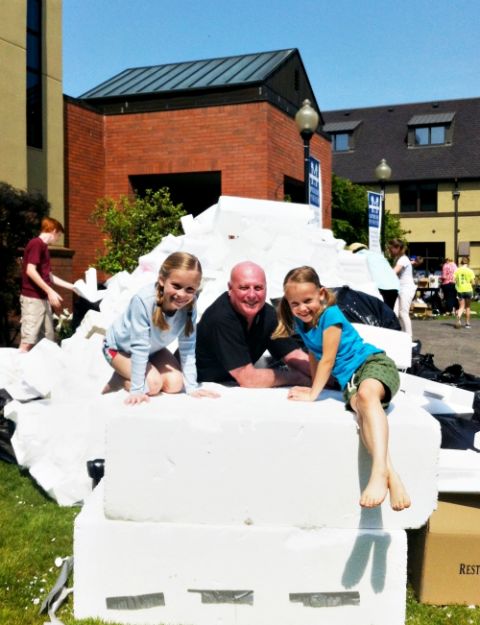 Fr. Michael Biewend, pastor at St. Mary Magdalene Church in Portland, Oregon, joins two young girls on top of a pile of plastic foam collected as part of an Earth Day recycling collection. (The Madeline Parish)