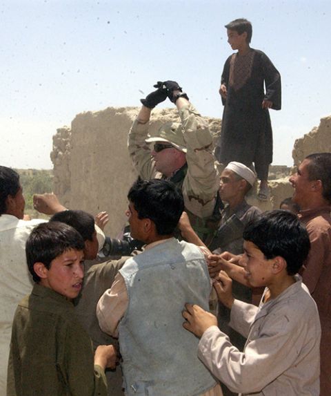 Sgt. Matthew MacRoberts passes out pens and pencils to children during a Humanitarian Assistance mission for Syed River flood victims outside Bagram, Afghanistan, June 30, 2005.