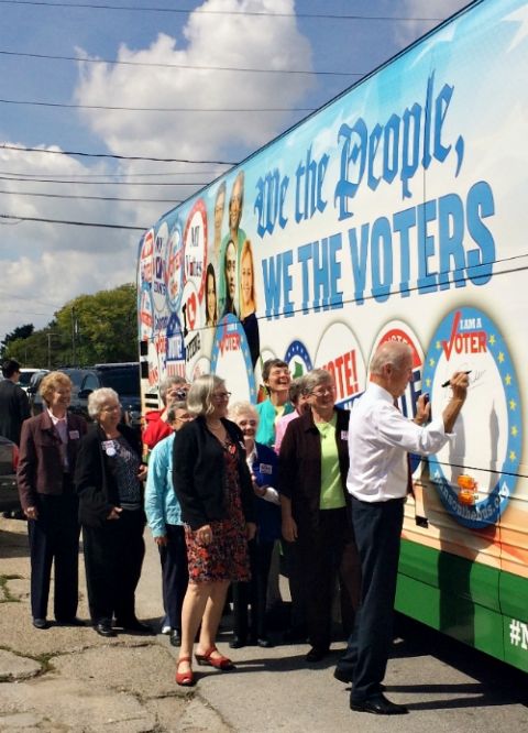 Vice President Joe Biden signs his name to the Network Nuns on the Bus official vehicle on Sept. 17, 2014, after speaking at the kick-off rally in front of the State Capitol in Des Moines, Iowa. Standing behind him is Social Service Sr. Simone Campbell.