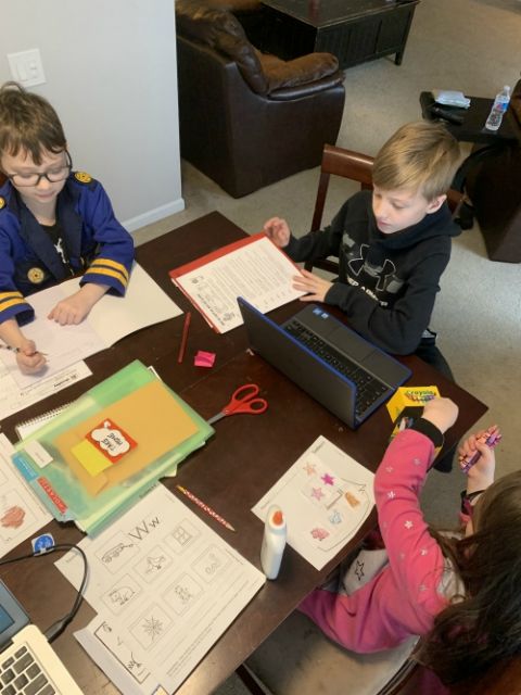 Siblings Jazon, Avri and Brayden work on class assignments at the dining room table. (Jamie Breeden)