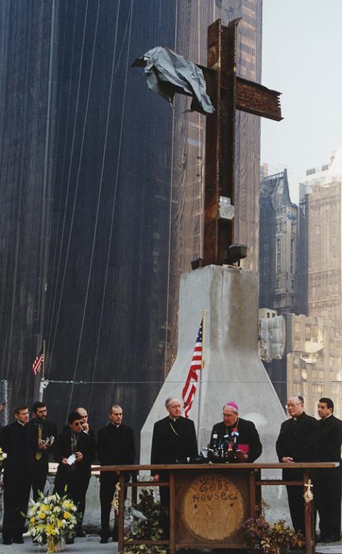 Archbishop Leonardo Sandri prays at ground zero June 20, 2002, in New York accompanied by Cardinal Edward Egan of New York Archbishop Leonardo Sandri (at podium), says a prayer at ground zero in New York while laying a wreath at the site June 20, 2002. He was accompanied by Cardinal Edward Egan of New York (center left). (CNS/Chris Sheridan)